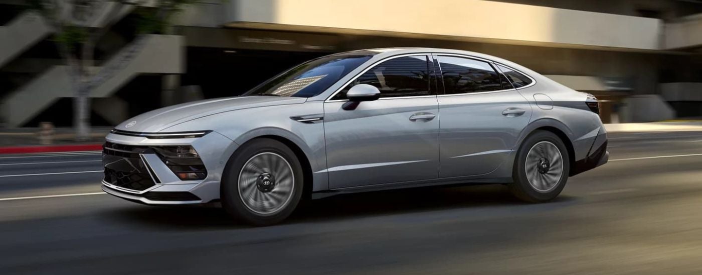 A silver 2024 Hyundai Sonata Hybrid Limited shown driving from the side.