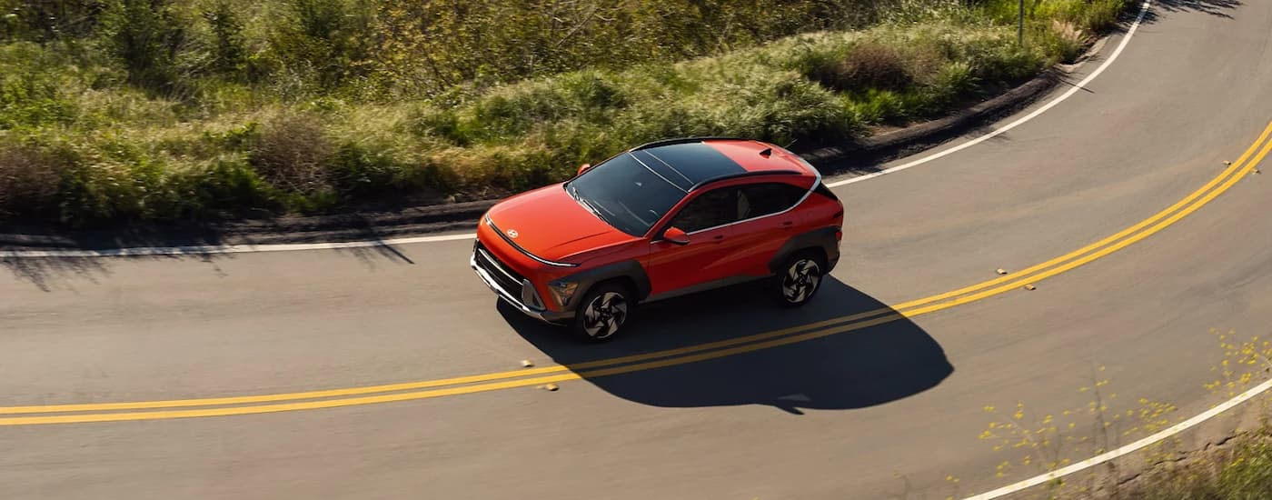 Orange 2026 Hyundai Kona driving on a winding road