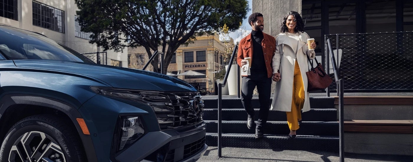 Smiling couple walking past a 2025 Hyundai Tucson