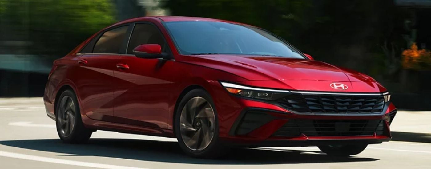 Red 2026 Hyundai Elantra driving on a paved road.