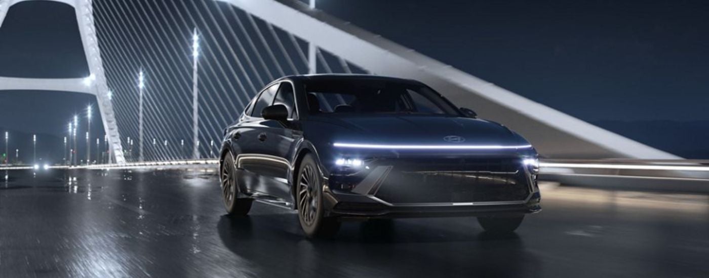 A black 2026 Hyundai Sonata driving over a bridge on a rainy night.