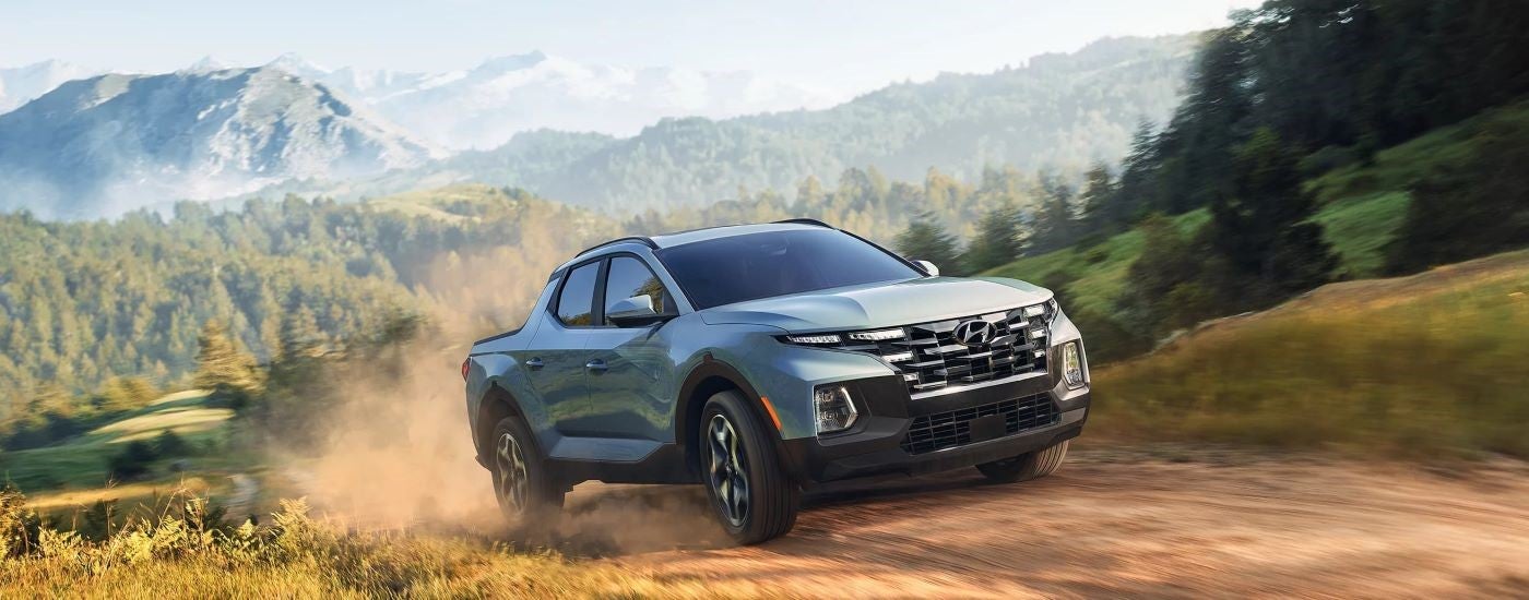 A blue 2023 Hyundai Santa Cruz driving off-road.