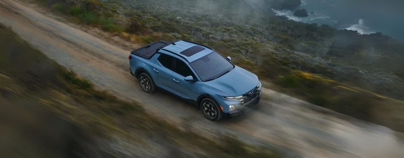 Blue 2022 Hyundai Santa Cruz shown from above driving a dirt road.